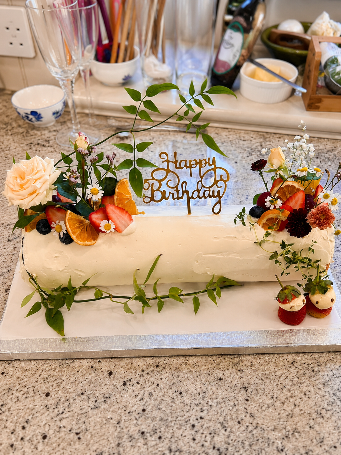 Celebration cake decorated with fruit, flowers and greenery