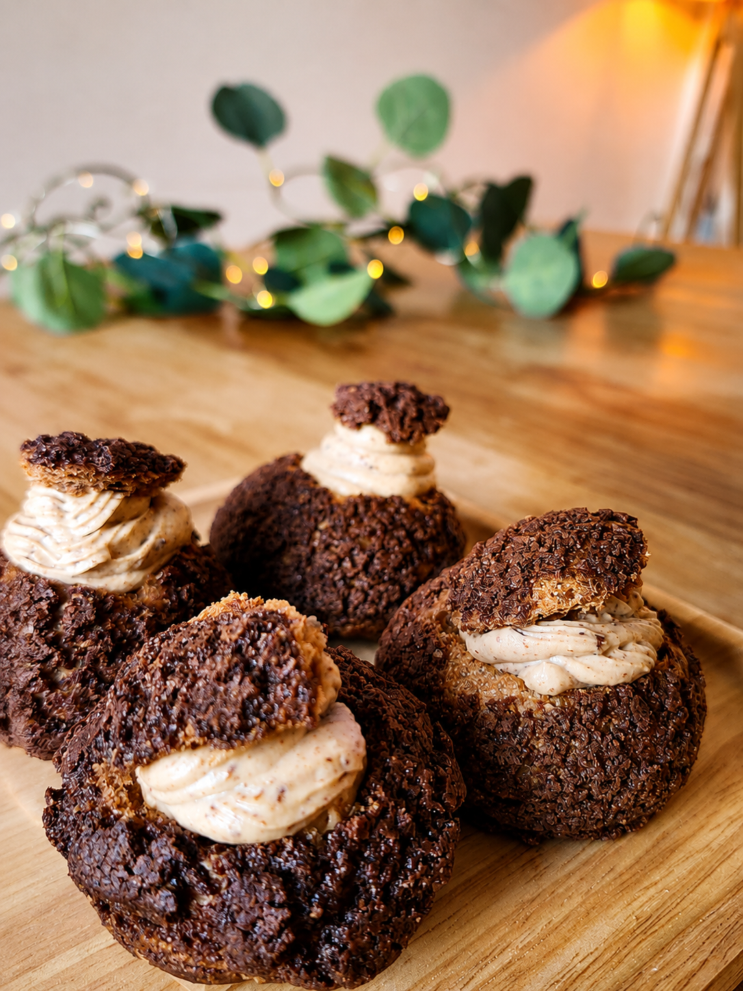 Chocolate choux creams on a wooden serving board